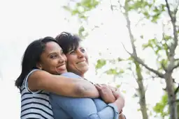 Adult woman embracing mother from behind