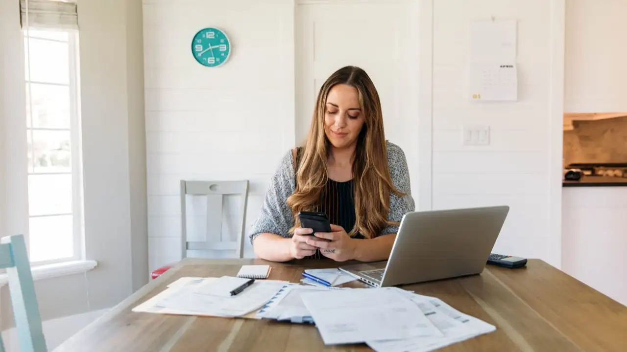 A woman sits at her dining room table using a debt payoff app.