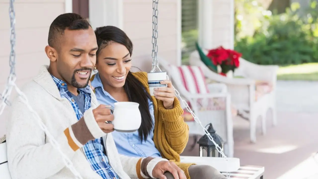 A young couple sitting on the porch swing of their home