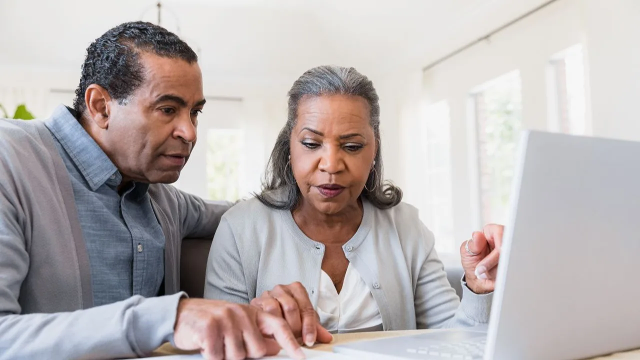 Couple in the living room checking the bank account on computer