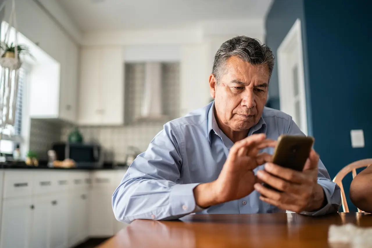 Senior man in kitchen using his phone