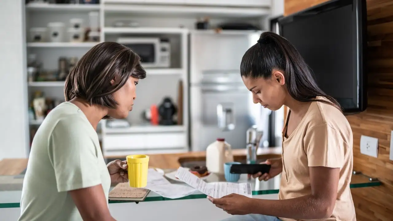 couple paying bills on the mobile phone during breakfast at home