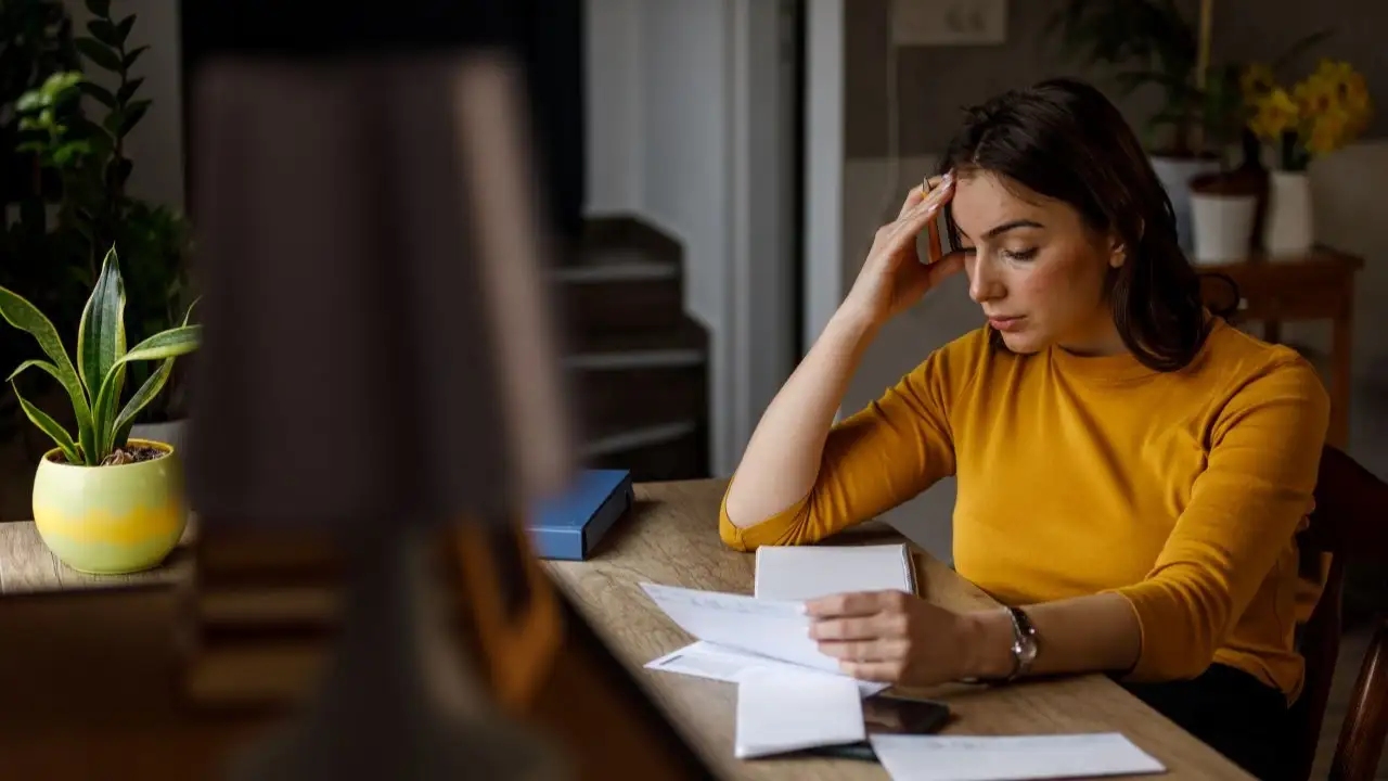 Young woman sorting out her monthly bills and struggling with finances