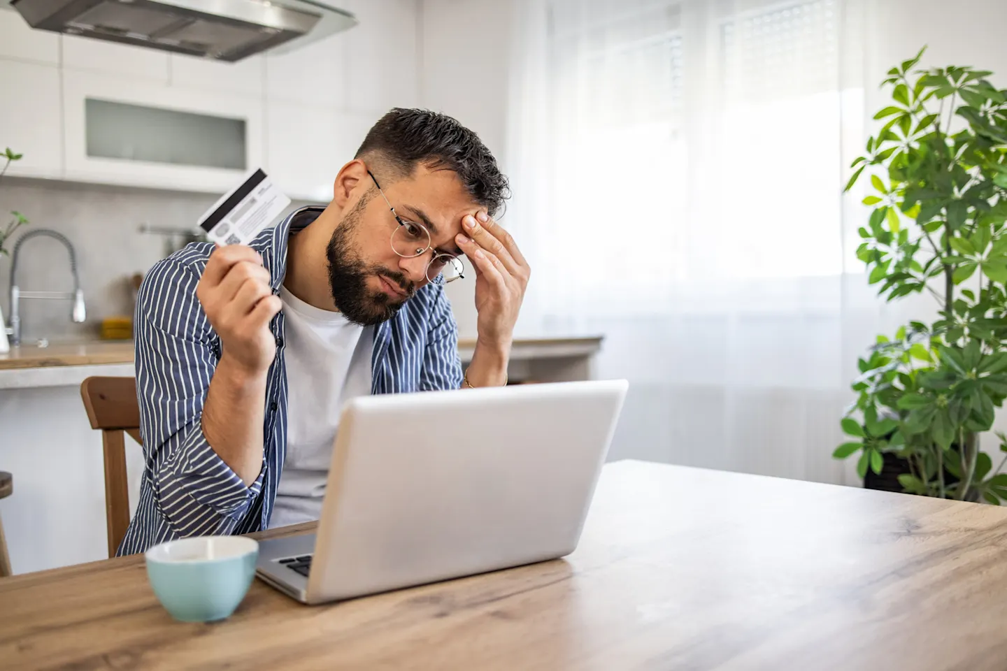 Man contemplates credit card balance.