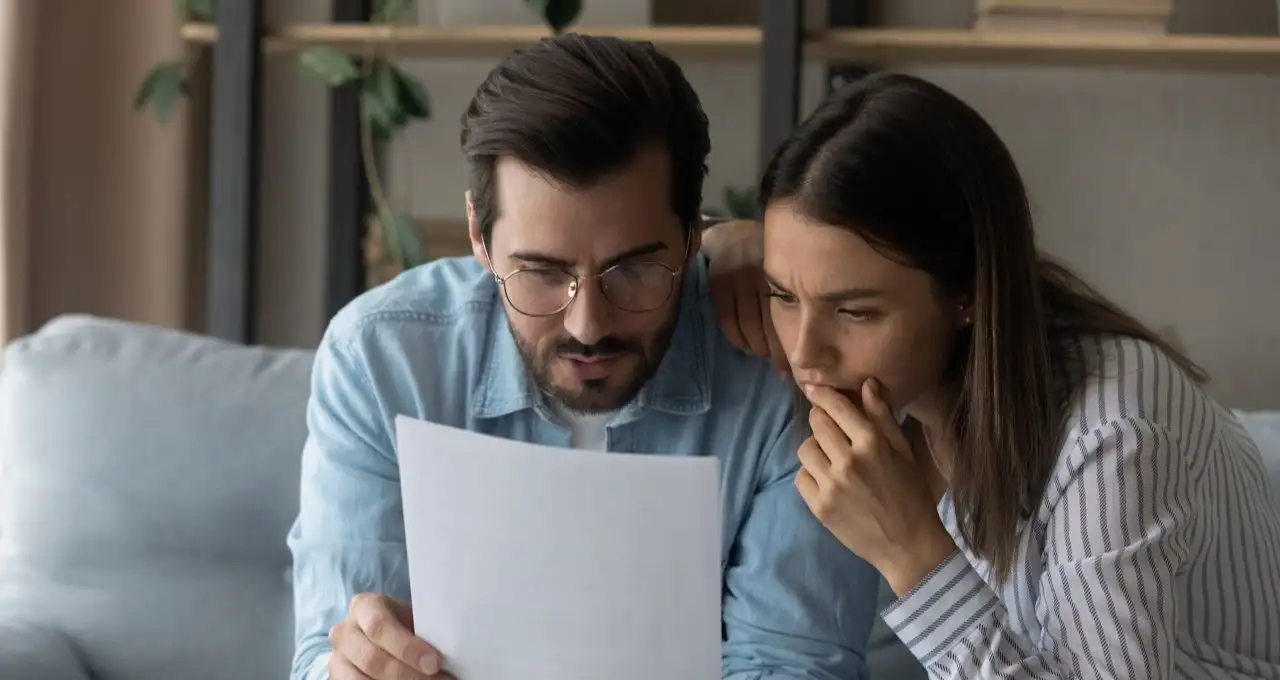 Close up puzzled focused couple reading letter together,