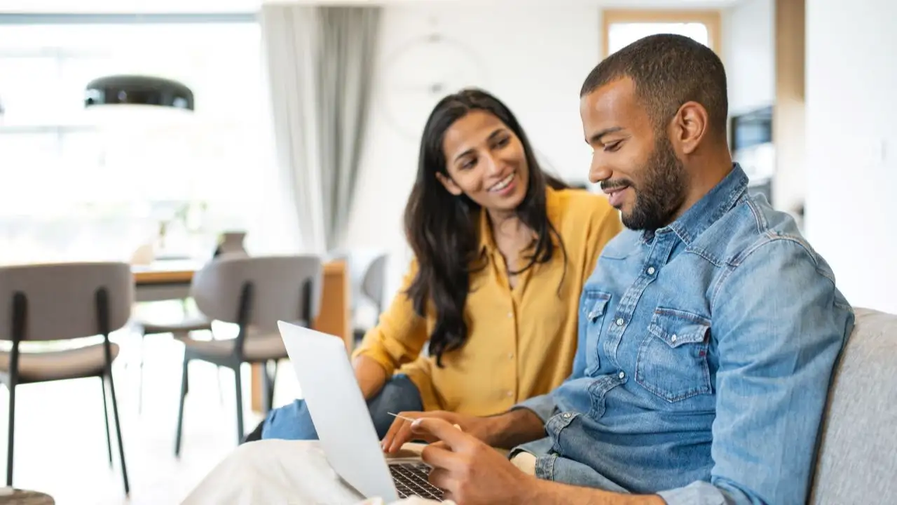 At the table in the living room, a couple examines debt consolidation loan while having a friendly conversation