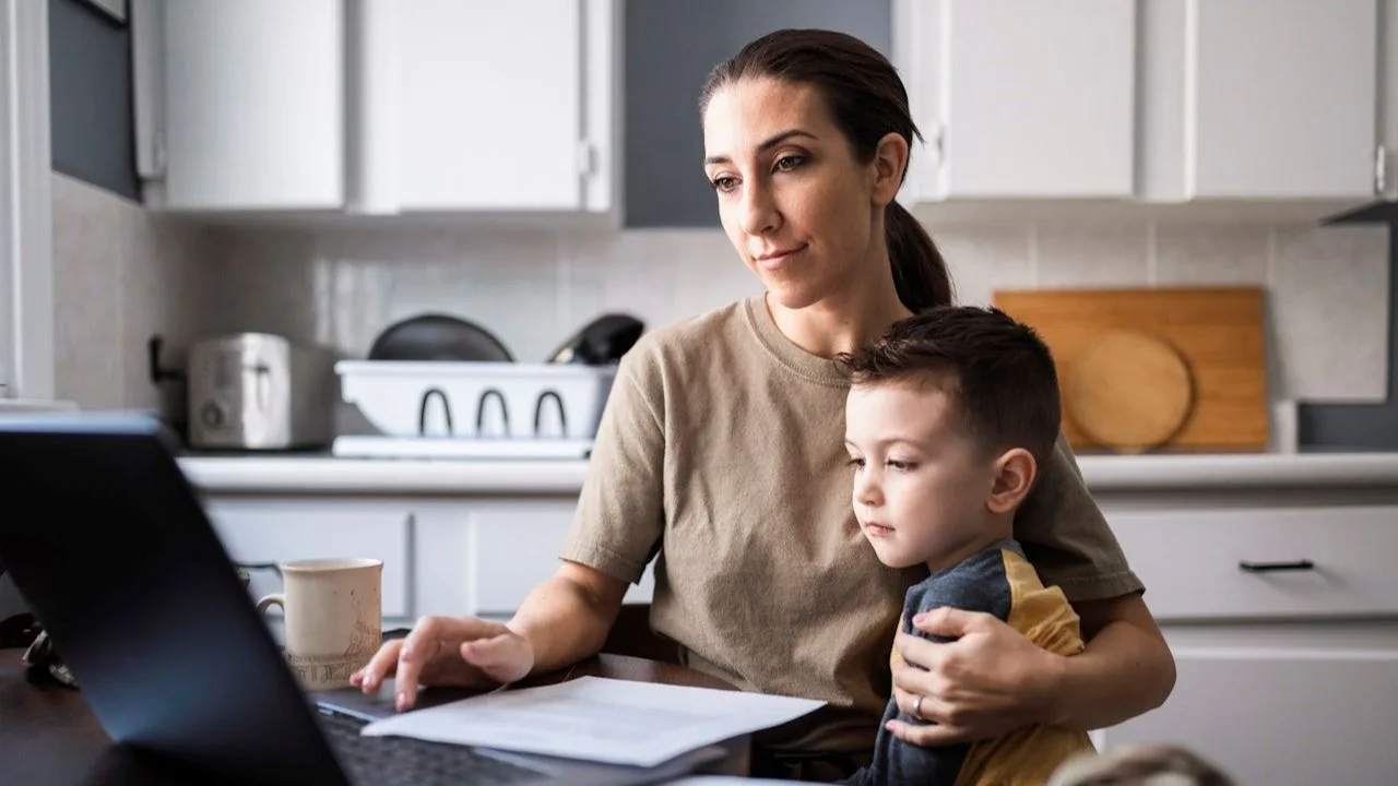 Mother with son in kitchen, shopping on internet for a personal loan