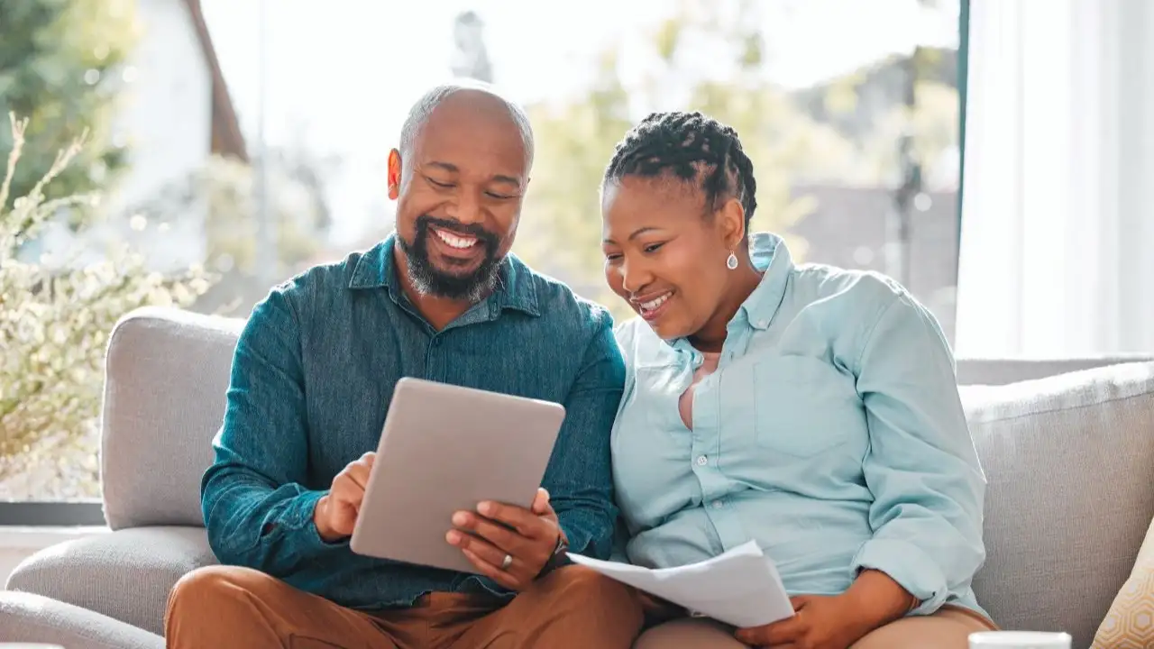 Couple looking through their bills while using a digital tablet