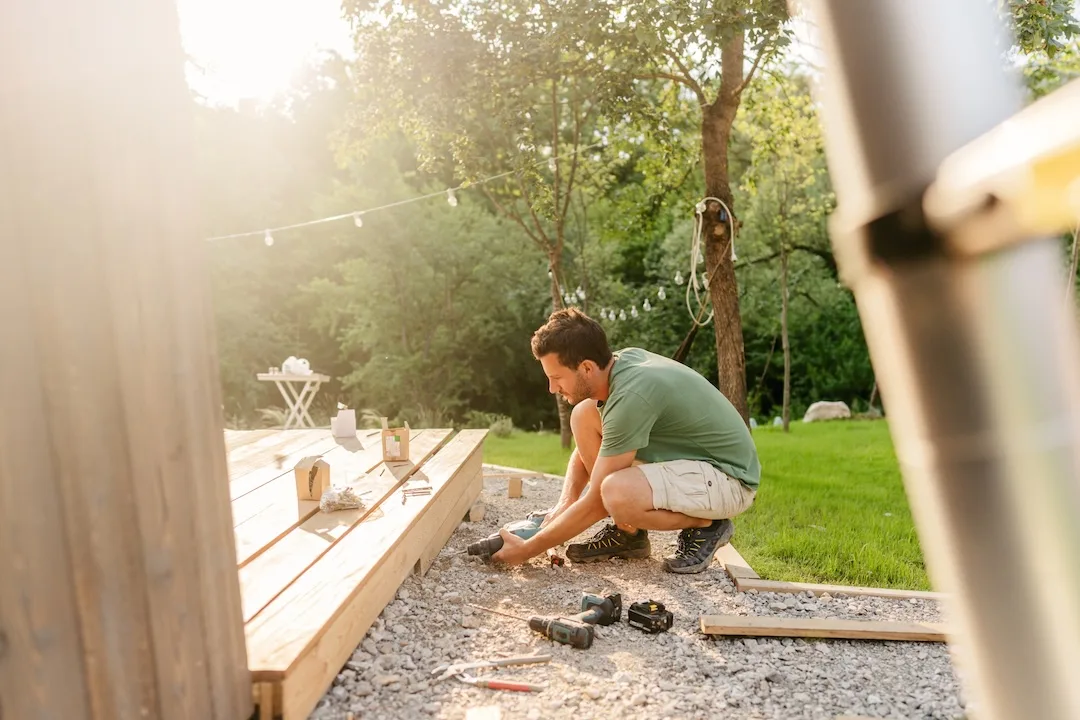 Man builds backyard deck. 