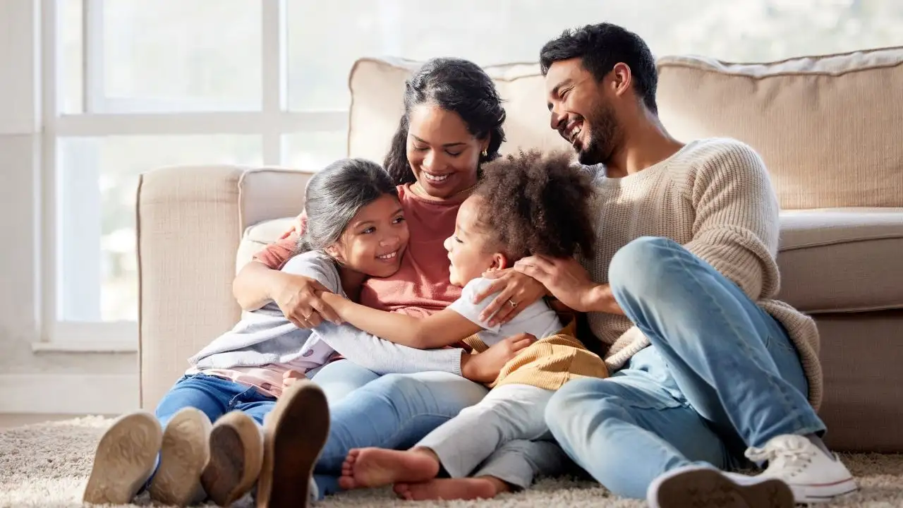 Happy family with two daughters hugging their mother and bonding at home.