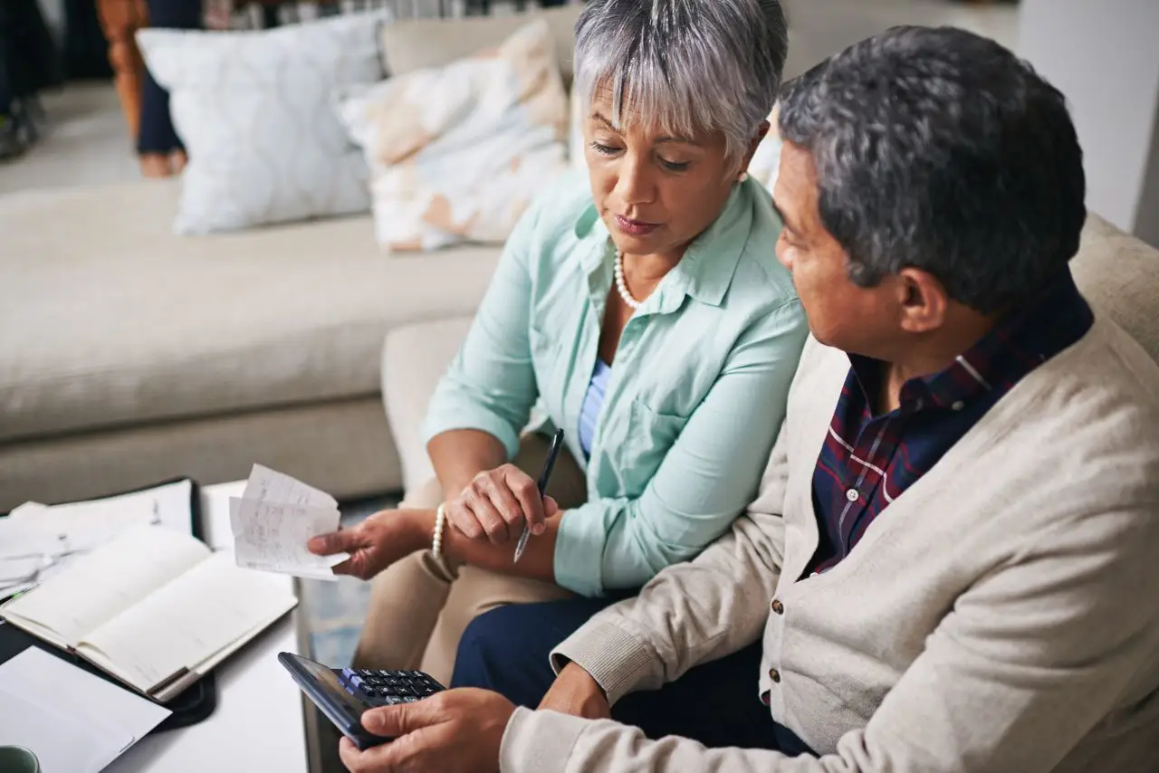 Couple working out a budget while sitting on the living room sofa