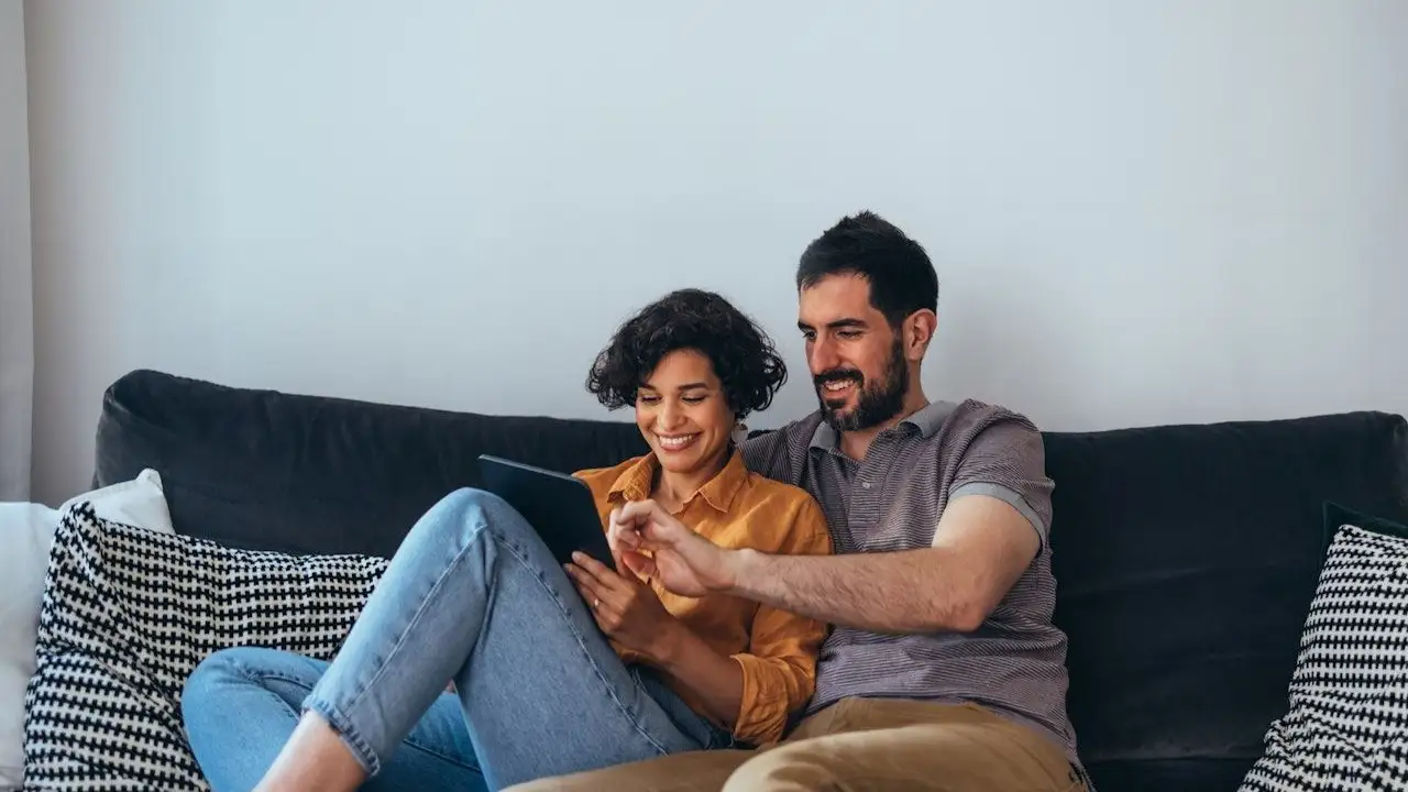 Couple smiling and reviewing their debt health on a tablet.