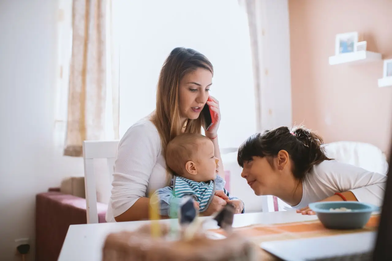 Mother with her baby boy and cute girl working from home